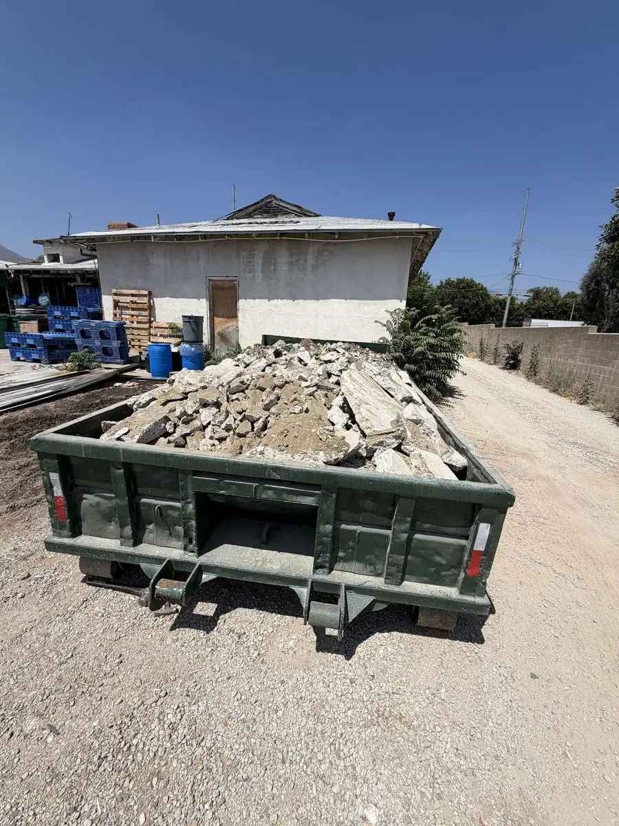 Green roll-off bin loaded with broken concrete rubble
